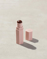 Opened Match Stix Contour Skinstick in the shade Ebony container on a grey background.