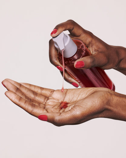 Deep skin toned model pumping cherry dub gel cleanser into hands.