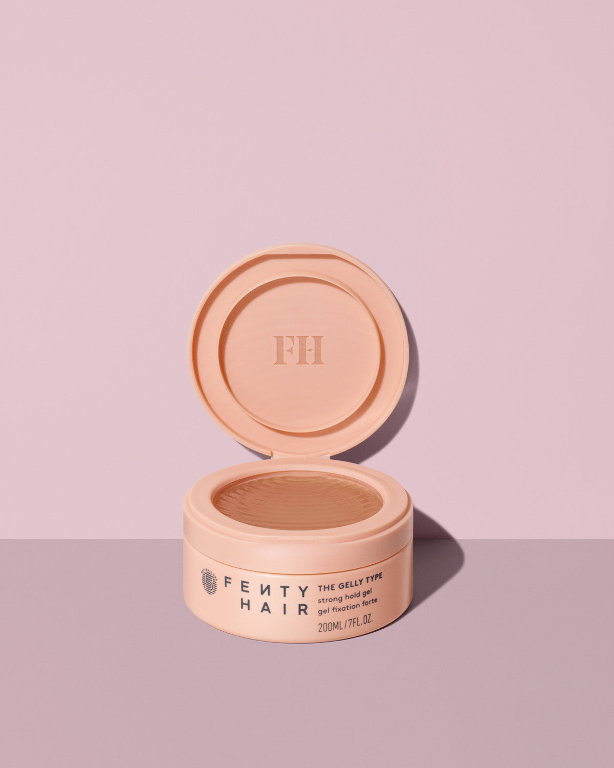 Fenty Hair The Gelly Type Strong Hold Gel tub open on a lavender background.